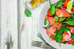 Fish salad. Salad with slices of salmon, tomatoes and spinach with lime juice. photo