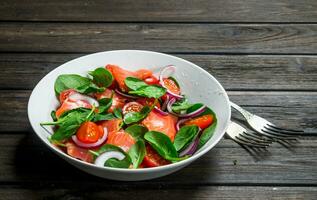 Fish salad. Salad with slices of salmon, tomatoes and spinach with lime juice. photo