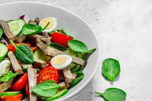 Healthy salad. Salad with boiled beef, vegetables and quail eggs. photo