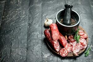 Different kinds of salami with spices and herbs. photo