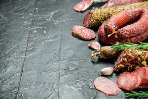 Assortment of different salami with spices and herbs. photo