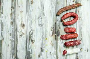 Assortment of different smoked salami with herbs and seasonings. photo