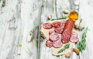 Sliced salami on paper with spices. photo