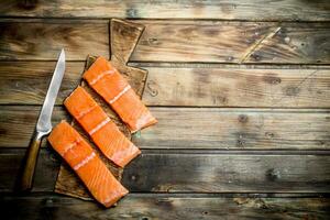 Raw salmon fish steaks on an old cutting Board. photo