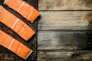 Raw salmon fish filet on an old cutting Board. photo