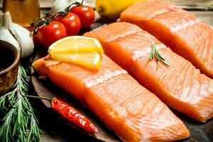 Raw salmon fish filet with lemon, tomatoes and herbs. photo