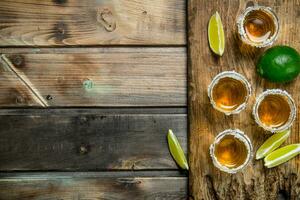 Tequila in a shot glass on a cutting Board with slices of lime. photo