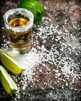 tequila en un Disparo vaso con sal y rebanadas de Fresco Lima. foto