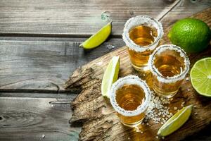 Tequila in a shot glass of salt on the cutting Board. photo