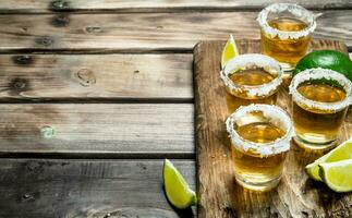 Tequila in a shot glass on a cutting Board with slices of lime. photo