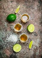 Tequila in a shot glass with salt and sliced lime. photo