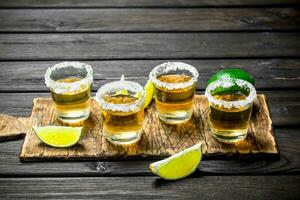 Tequila in a shot glass on a cutting Board with slices of lime. photo