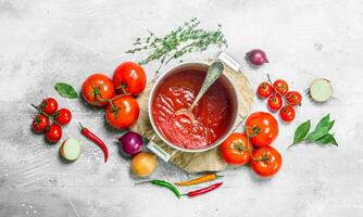 Tomato sauce in a pot of herbs and fresh tomatoes. photo