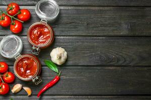 Tomato sauce in a jar with garlic and cherry tomato branches. photo