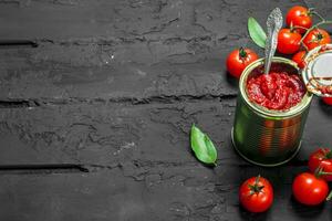 Tomato sauce in a tin can with a spoon. photo