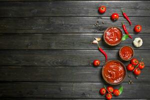 Tomato sauce in bowl and red hot pepper. photo