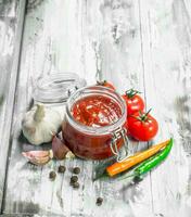 Tomato sauce in a jar and spices. photo