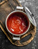 tomate salsa en un maceta en un corte tablero. foto