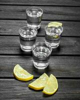 Vodka in a shot glass and lemon slices. photo