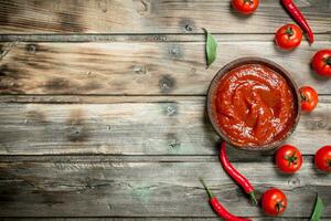 Tomato sauce in bowl with red hot pepper. photo