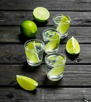 Vodka and slices of fresh lime in a shot glass. photo