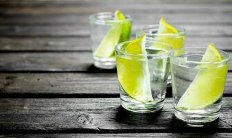 Vodka with lime slices in a shot glass. photo