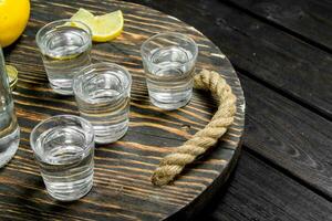 Vodka on a tray with lemon. photo