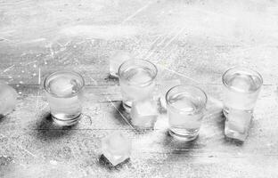 Vodka in a shot glass and ice cubes. photo