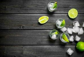 Vodka with ice and lime slices in a shot glasses. photo