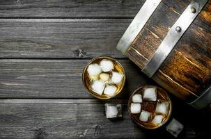 Whiskey with ice and a wooden barrel. photo