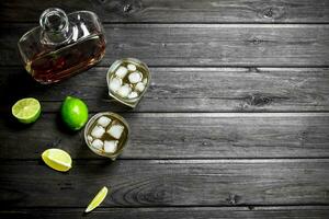 Whiskey in a bottle and glasses of ice and slices of lime. photo