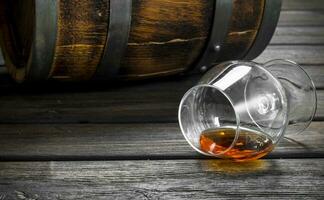 Cognac in a glass and a barrel. photo