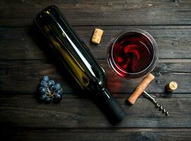 glass of red wine with a corkscrew and corks. photo