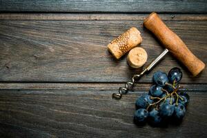 Corkscrew with corks and grapes. photo
