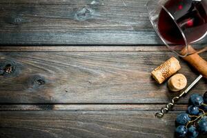 vino antecedentes. un vaso de rojo vino con un sacacorchos y un enredadera. foto