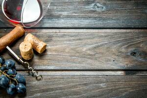 Wine background. A glass of red wine with a corkscrew and a vine. photo