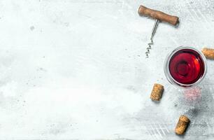 Wine background. A glass of red wine and a corkscrew. photo