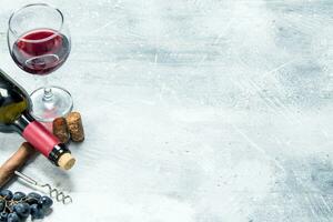 Wine background. Red wine with a grapes and a corkscrew. photo