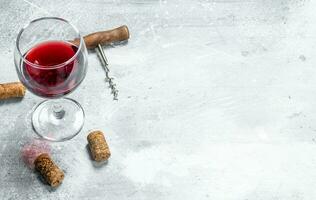 Wine background. A glass of red wine and a corkscrew. photo