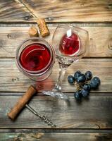 Red wine in a glass with grapes and a corkscrew. photo