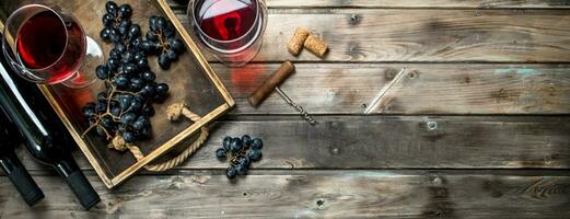 Red wine in a glass with grapes and a corkscrew. photo