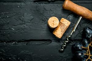 Wine background. Corkscrew with a branch of grapes and corks. photo