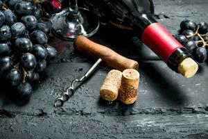 Wine background. Red wine with grapes and corkscrew. photo