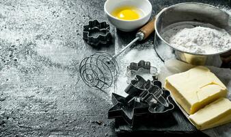 Baking background. Flour with egg, butter and various forms for baking. photo