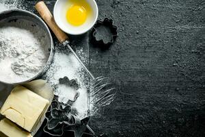 Baking background. Flour with egg, butter and various forms for baking. photo