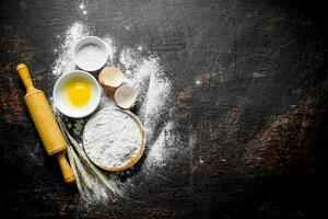 Flour with egg and a rolling pin. photo