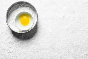 Flour in a sieve with egg in a bowl. photo