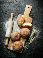 Fresh buns on a wooden cutting Board with a rolling pin and spikelets. photo