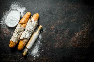 Fresh French baguette with flour and rolling pin. photo