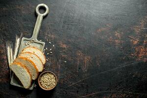 Pieces of bread on a cutting Board with grains and spikelets. photo